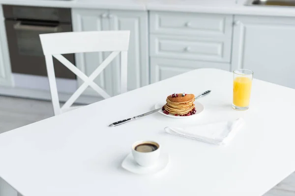 Delicious pancakes, fresh orange juice and coffee served on kitchen table — Stock Photo