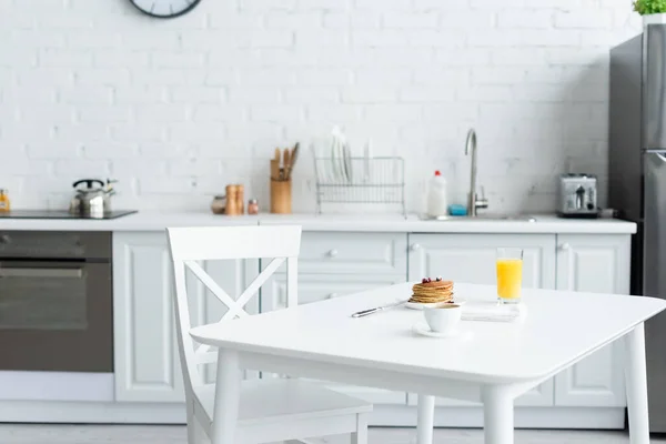 Panquecas saborosas, café e suco de laranja na mesa branca na cozinha moderna — Fotografia de Stock