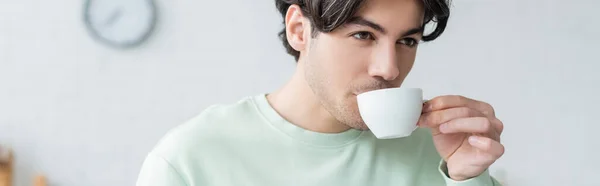 Joven morena hombre beber café de blanco taza, bandera - foto de stock