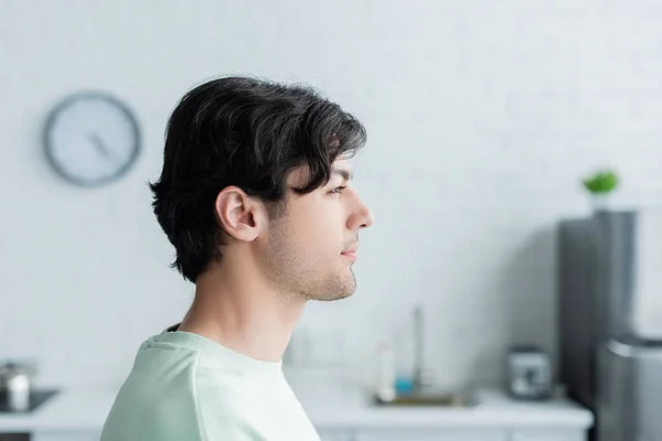 Seitenansicht eines jungen brünetten Mannes in verschwommener Küche — Stockfoto