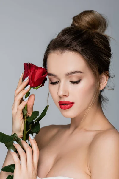 Sensual woman with naked shoulders and makeup holding red rose isolated on grey — Stock Photo