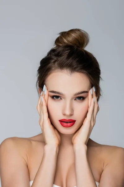 Charming woman with perfect skin and red lips looking at camera isolated on grey — Stock Photo