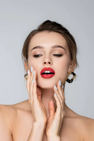 Sinnliche junge Frau mit roten Lippen berühren Gesicht isoliert auf grau — Stockfoto