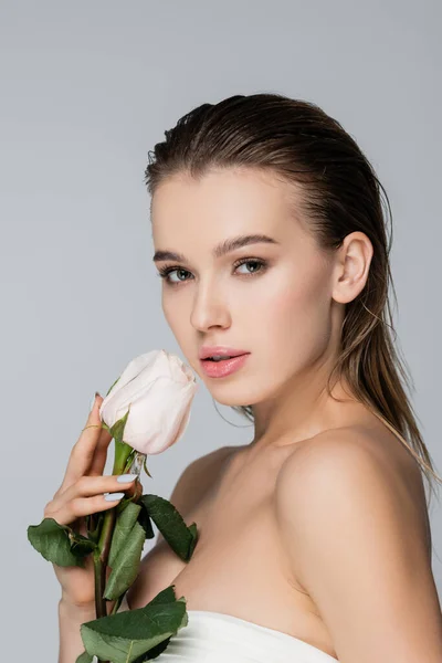 Чарівна жінка з ідеальною шкірою, що тримає білу троянду ізольовано на сірому — стокове фото