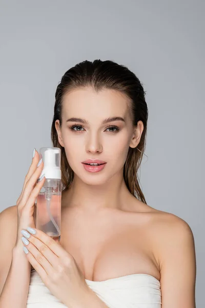 Mujer joven con cara de espuma mirando a la cámara aislada en gris - foto de stock