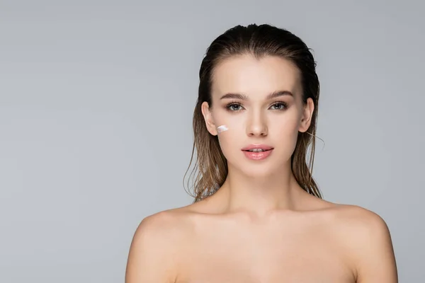 Charming woman with wet hair, naked shoulders and cosmetic cream on face isolated on grey — Stock Photo