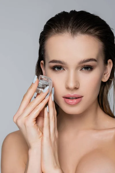 Young woman with perfect skin holding ice cube isolated on grey — Stock Photo