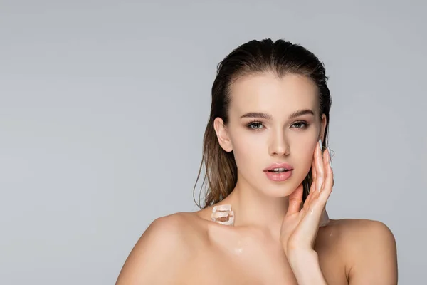 Charming woman with ice cube on bare shoulder looking at camera isolated on grey — Stock Photo