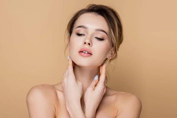 Mujer joven con maquillaje natural y hombros desnudos aislados en beige - foto de stock