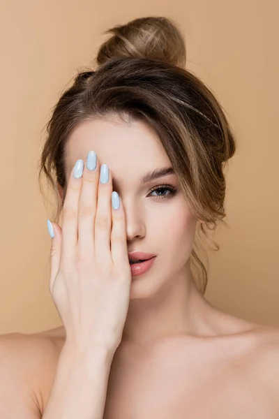 Young woman obscuring face with hand while looking at camera isolated on beige — Stock Photo