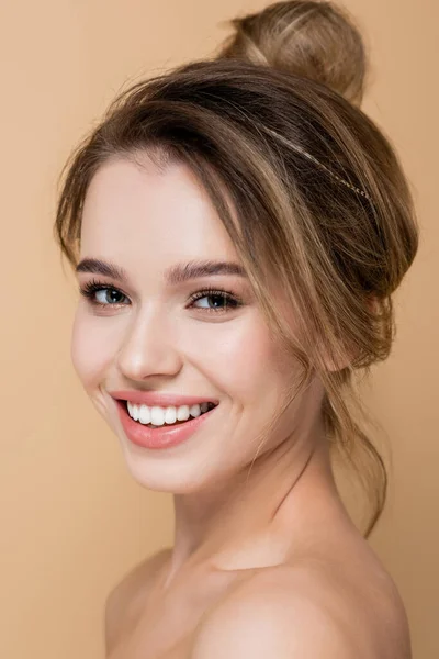 Vista de cerca de la encantadora mujer con maquillaje natural sonriendo a la cámara aislada en beige - foto de stock