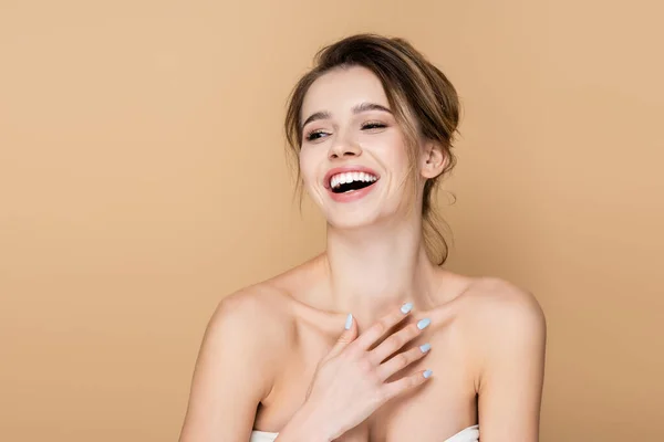 Junge Frau mit nackten Schultern, die wegschaut und vereinzelt auf beige lacht — Stockfoto