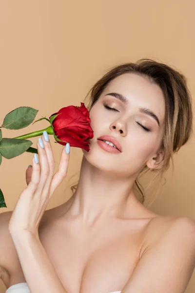 Pretty woman with naked shoulders and natural makeup near red rose isolated on beige — Stock Photo