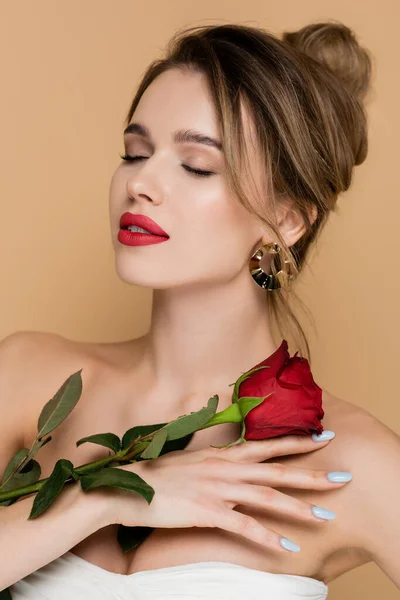 Mulher encantadora com olhos fechados posando com rosa vermelha isolada no bege — Fotografia de Stock