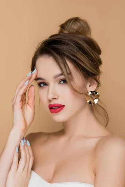 Young woman with makeup and bare shoulders looking at camera isolated on beige — Stock Photo