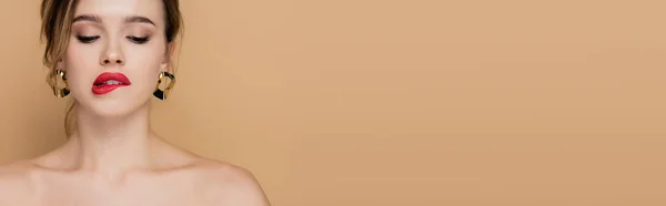 Sensual woman with naked shoulders biting lip isolated on beige, banner — Stock Photo