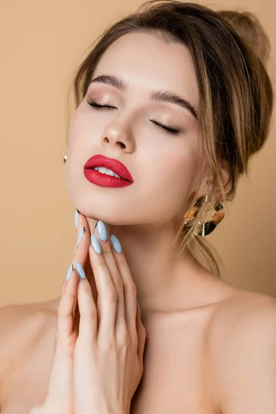 Bonita mujer con maquillaje posando con los ojos cerrados aislados en beige - foto de stock