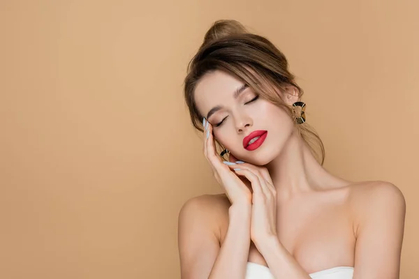 Young woman in strapless top posing with closed eyes isolated on beige — Stock Photo