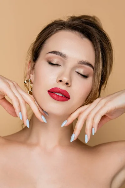 Young and sensual woman with red lips and closed eyes touching face isolated on beige — Stock Photo