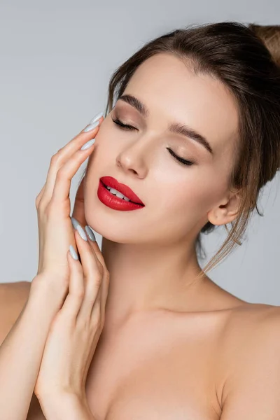 Bonita mujer con labios rojos, ojos cerrados y manos cerca de la cara aislada en gris - foto de stock