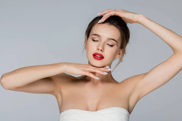 Young woman in strapless top posing with closed eyes isolated on grey — Stock Photo