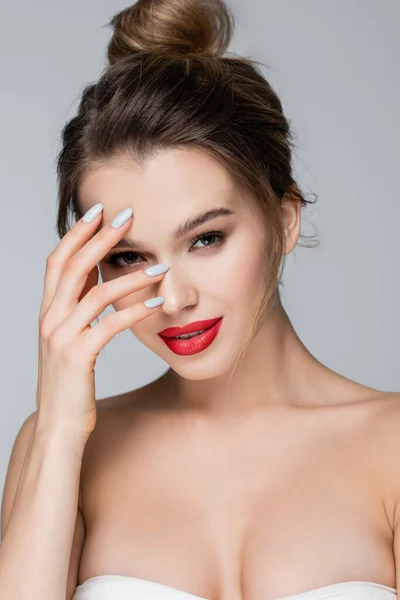 Femme souriante aux épaules nues posant avec la main près du visage isolé sur gris — Photo de stock