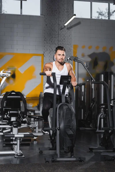 Young sportsman training on elliptical trainer in sports center — Stock Photo