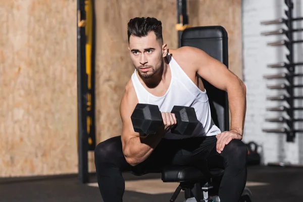Sportsman working out with dumbbell in gym — Stock Photo