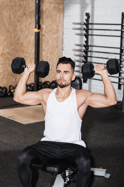 Uomo in abbigliamento sportivo che si allena con i manubri in palestra — Foto stock