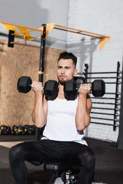 Athletic sportsman working out with dumbbells in gym — Stock Photo