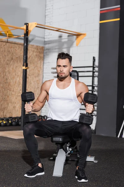 Focused sportsman training with dumbbells in sports center — Stock Photo