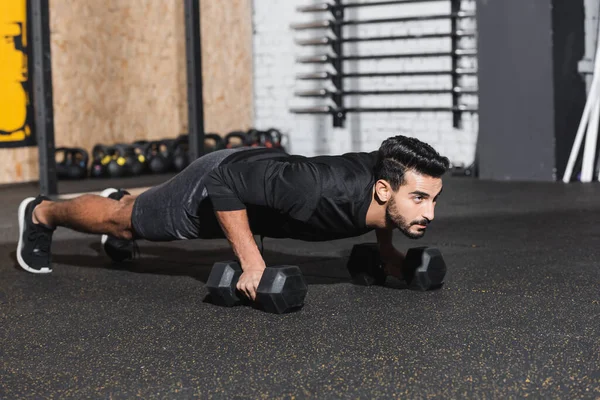 Esportista árabe fazendo press ups com halteres no ginásio — Fotografia de Stock