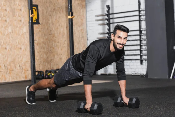 Sonriente deportista árabe entrenando con pesas en centro deportivo - foto de stock