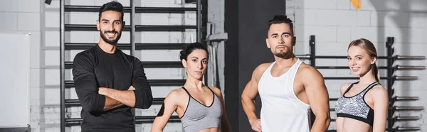 Deportistas y deportistas interraciales sonriendo a la cámara en el gimnasio, pancarta - foto de stock