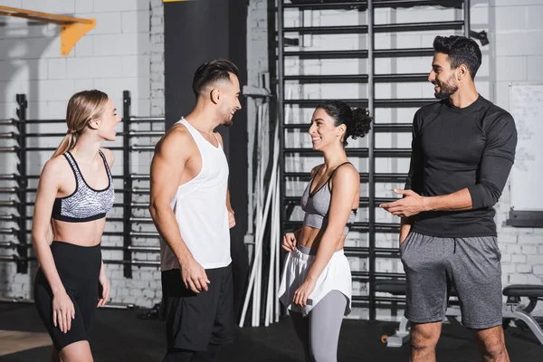 Positive interracial friends in sportswear talking in gym — Stock Photo