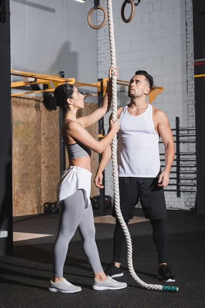 Interracial people in sportswear standing near climbing rope in sports center — Stock Photo