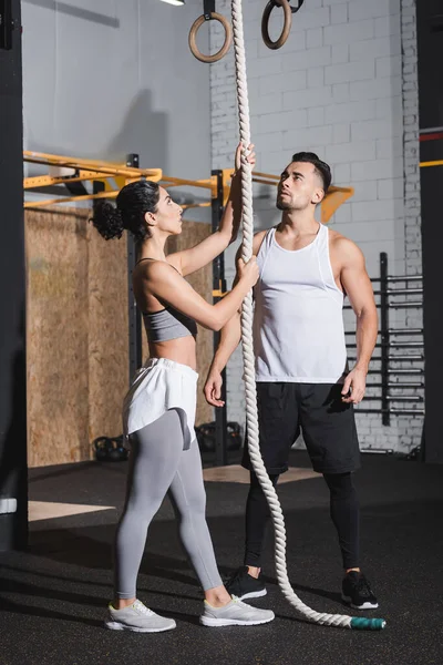 Interracial personnes en vêtements de sport debout près de la corde d'escalade dans le centre sportif — Photo de stock