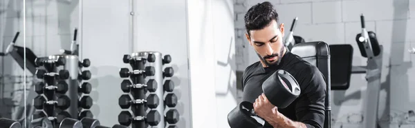 Bärtiger muslimischer Sportler trainiert mit Hantel im Fitnessstudio, Banner — Stockfoto