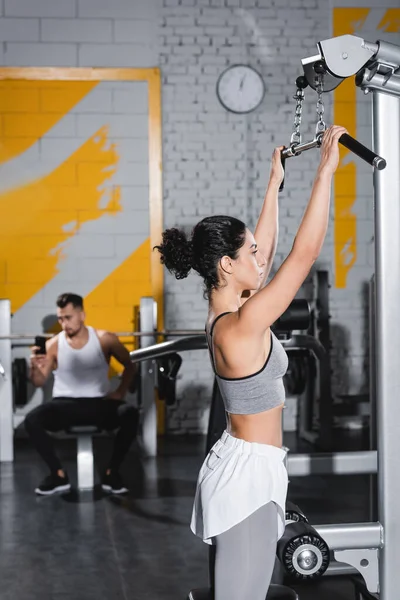 Entrenamiento de mujer de Oriente Medio en la máquina de extracción de lat en el gimnasio - foto de stock