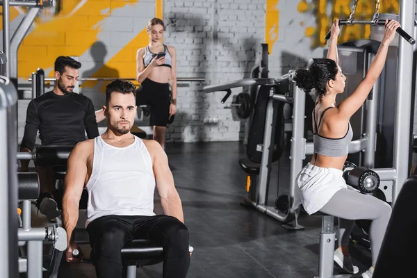 Jóvenes interraciales trabajando con equipos en un centro deportivo - foto de stock