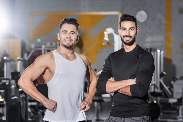 Souriants sportifs interracial regardant la caméra dans la salle de gym floue — Photo de stock