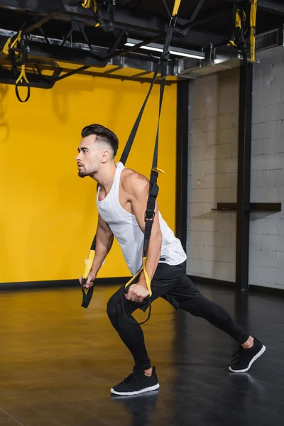 Jovem desportista treinando com tiras de suspensão no centro esportivo — Fotografia de Stock