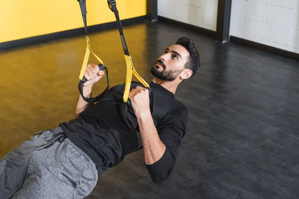 Бородатый мусульманский спортсмен тренируется с подвесными ремнями в тренажерном зале — стоковое фото