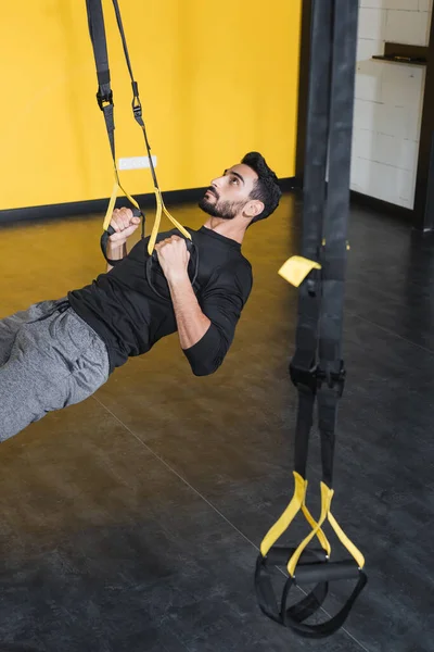 Entrenamiento de deportista musulmán con correas de suspensión en el gimnasio - foto de stock