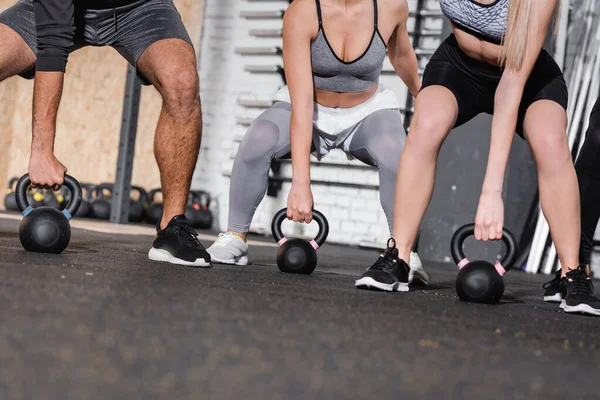 Vue recadrée des personnes travaillant avec des kettlebells dans le centre sportif — Photo de stock