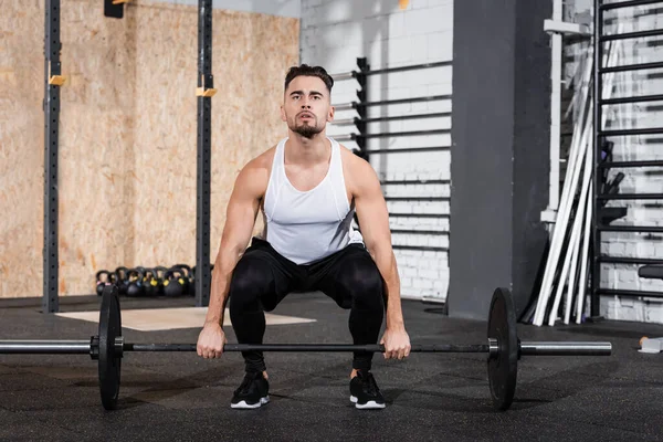 Athletic sportsman training with barbell in gym — Stock Photo