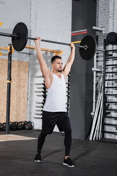 Athletic sportsman lifting barbell in gym — Stock Photo