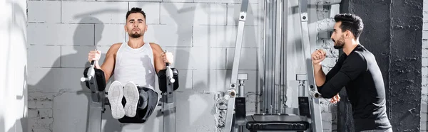 Allenamento di giovani sportivi su sbarre parallele vicino all'allenatore musulmano in palestra, banner — Foto stock