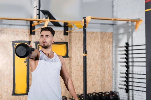 Athletic sportsman working out with kettlebell in blurred gym — Stock Photo