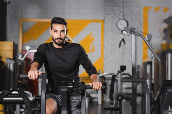 Muslim sportsman looking at camera while training on elliptical trainer — Stock Photo
